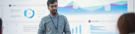 man in front of a large display training people about cyber security.