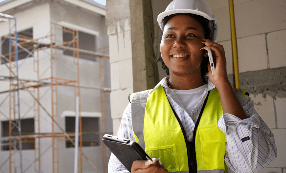 Engineer on a construction site using a phone and holding a tablet